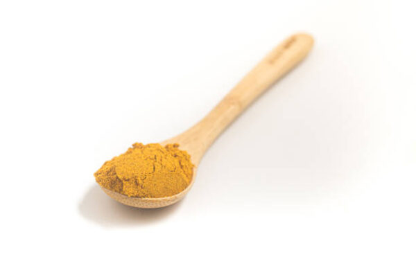 Curry powder into a teaspoon. measuring spoon on white background