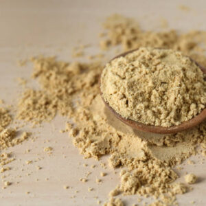 Spoon with aromatic mustard powder on wooden table, closeup. space for text