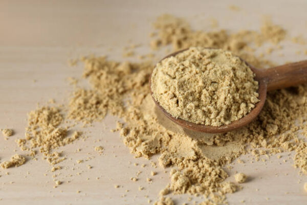 Spoon with aromatic mustard powder on wooden table, closeup. space for text