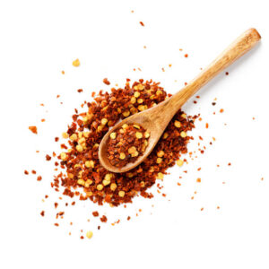 Crushed red chili pepper in wooden spoon isolated on white background. top view