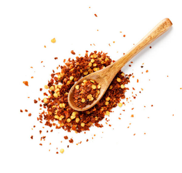 Crushed red chili pepper in wooden spoon isolated on white background. top view