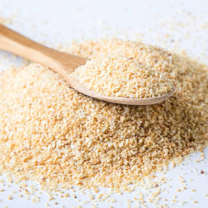 Garlic powder on white table with spoon